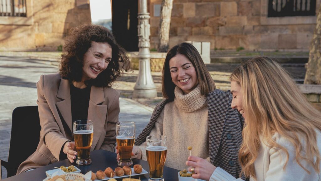 Group of friends sitting around a table laughing and eating Spanish food.